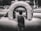 A child stands facing an inflatable play structure, which appears to be part of a bounce house setup. The scene is outdoors, with a crowd of people blurred in the background. The image is captured in black and white, highlighting textures and contrasts.