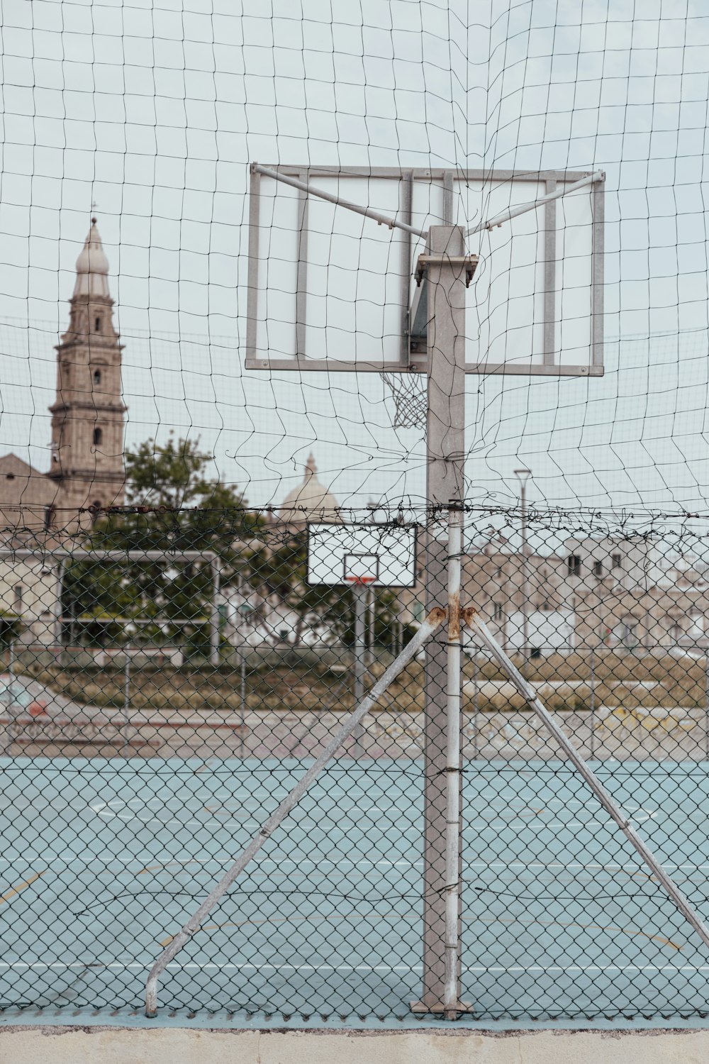 a basketball hoop in front of a fence with a clock tower in the background