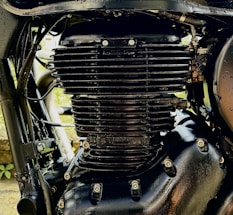 Close-up view of a black motorcycle engine with visible fins and bolts, highlighting the intricate mechanical details and metallic texture.