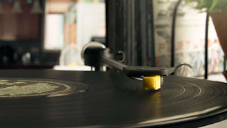 Close-up of a vintage turntable spinning a vinyl record with city skyline blurred in background.