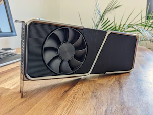 A close-up of a vintage graphics card resting on a wooden desk beside an old typewriter.