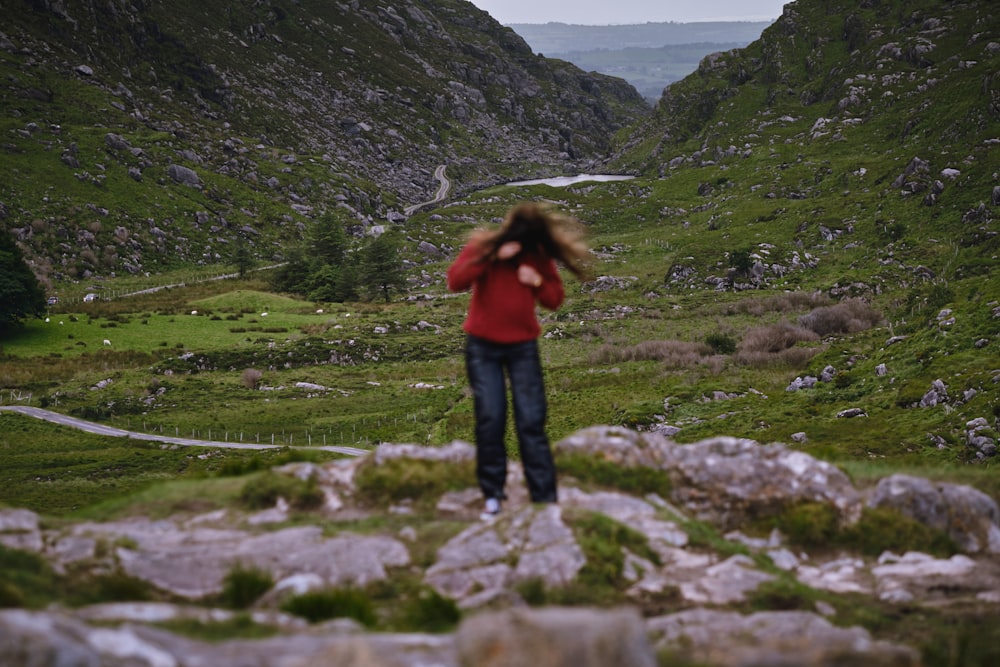 a woman standing on top of a lush green hillside