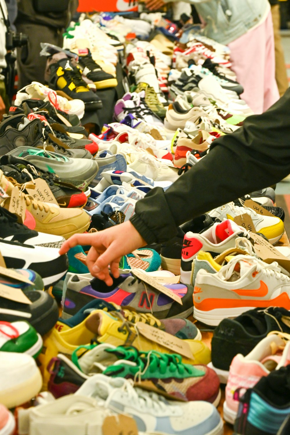 a person reaching for a shoe in a pile of shoes