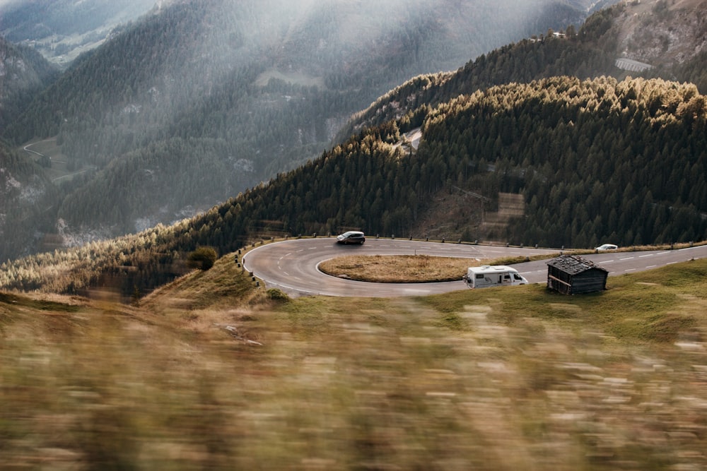 two trucks driving down a winding road in the mountains