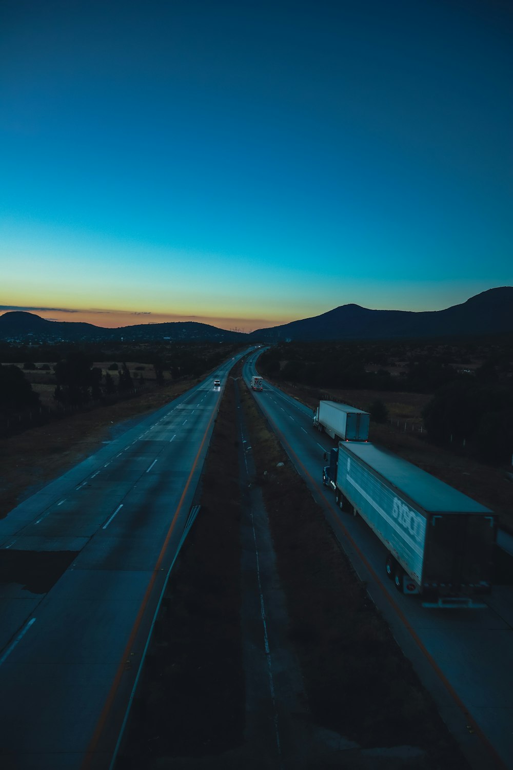 a semi truck driving down a highway at dusk