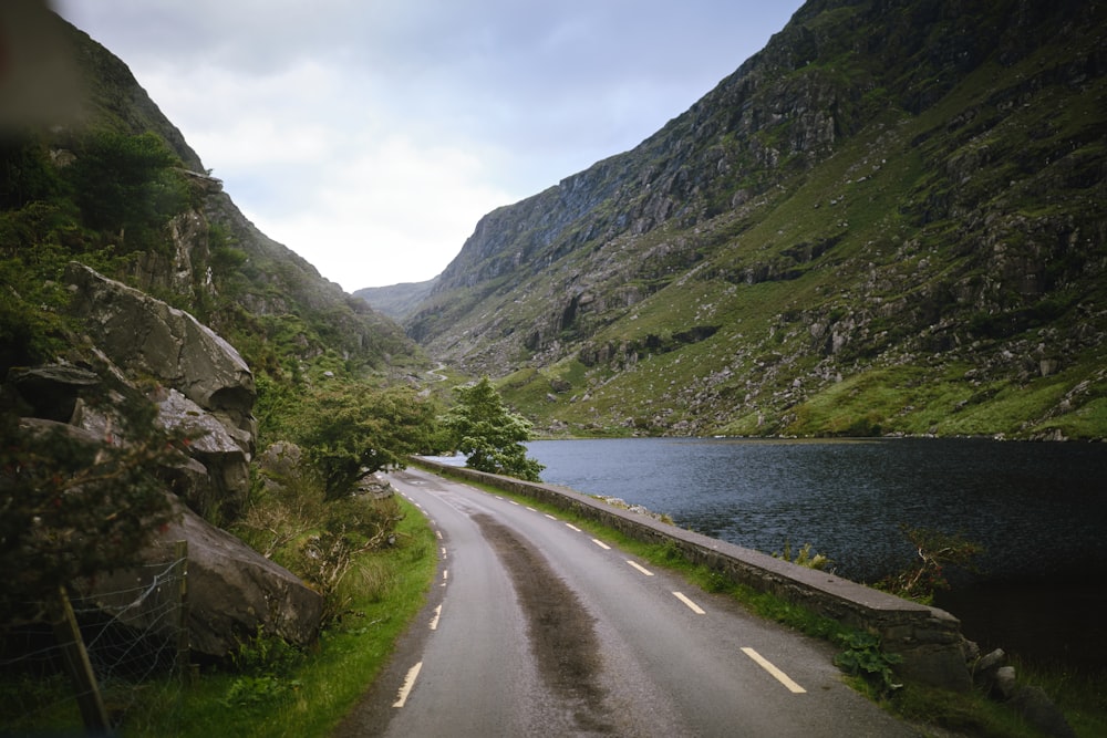 a car driving down a road next to a mountain