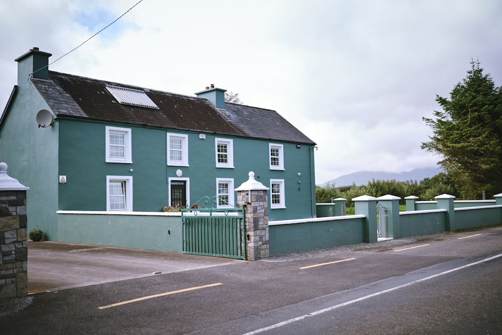 a green house with white windows and a fence