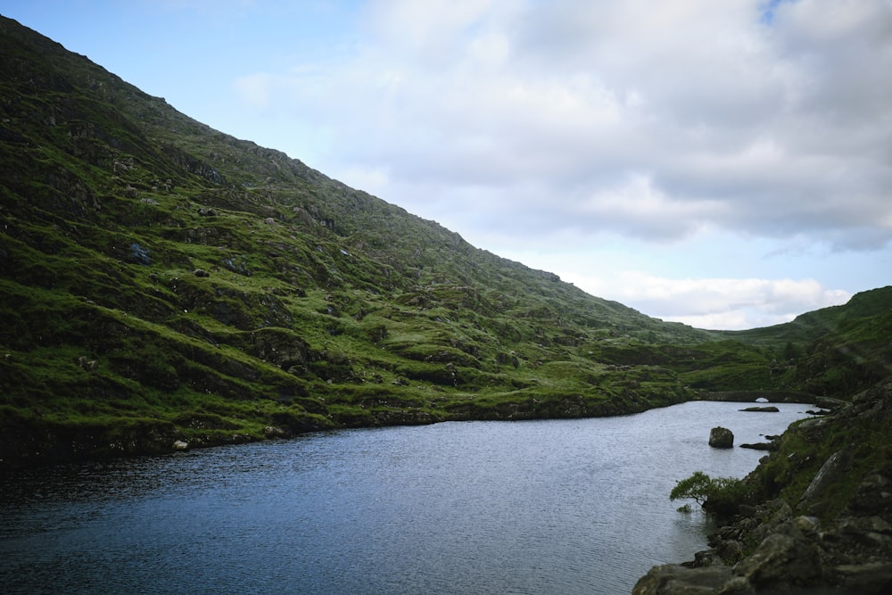 a body of water surrounded by a lush green hillside