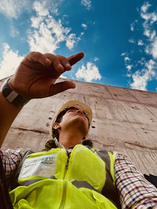 A construction worker wearing a hard hat, looking concerned while holding his injured arm.