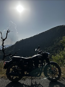 A shiny motorcycle parked on a scenic road with rolling hills in the background.