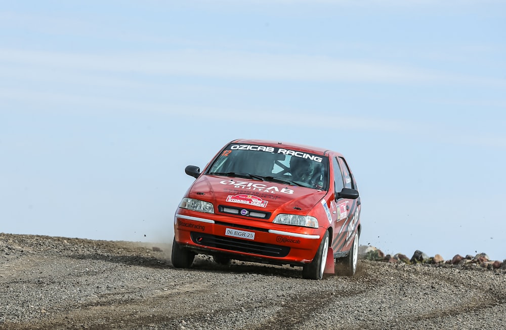 a red car driving down a dirt road