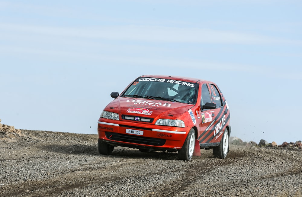 a red car driving down a dirt road