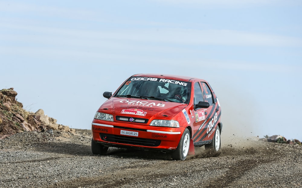 a red car driving down a dirt road