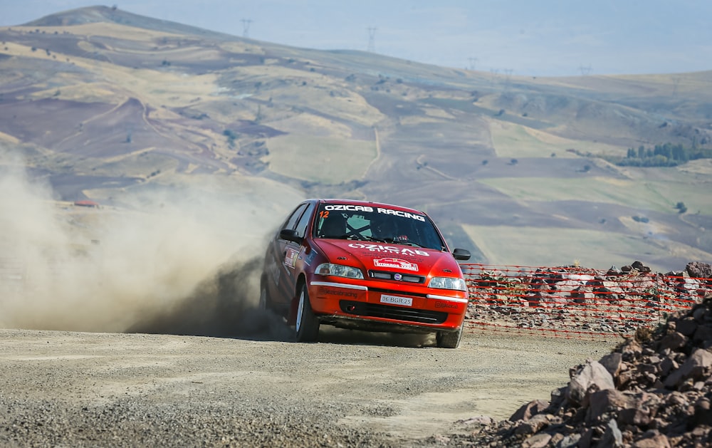 a red car driving down a dirt road