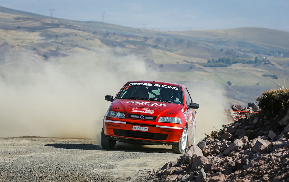 a red car driving down a dirt road