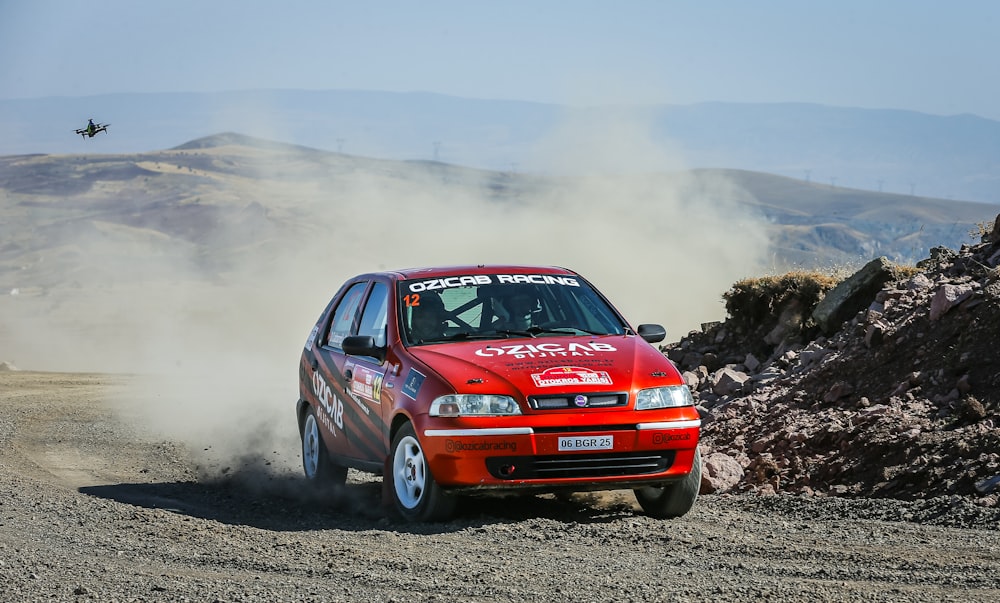 a red car driving down a dirt road