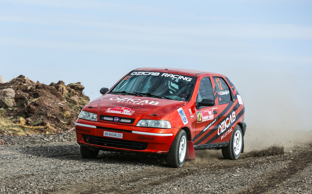 a red car driving down a dirt road