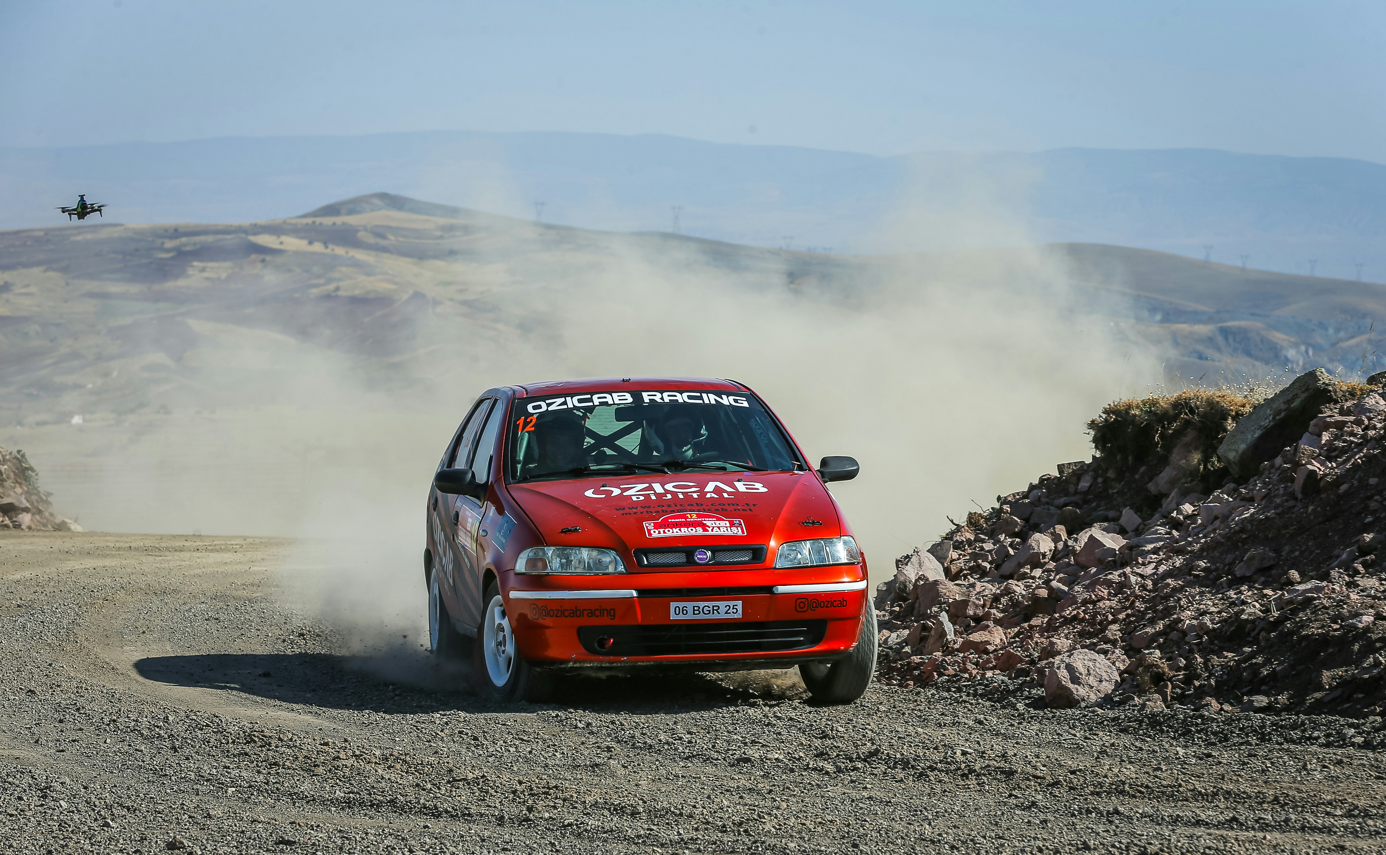 a red car driving down a dirt road