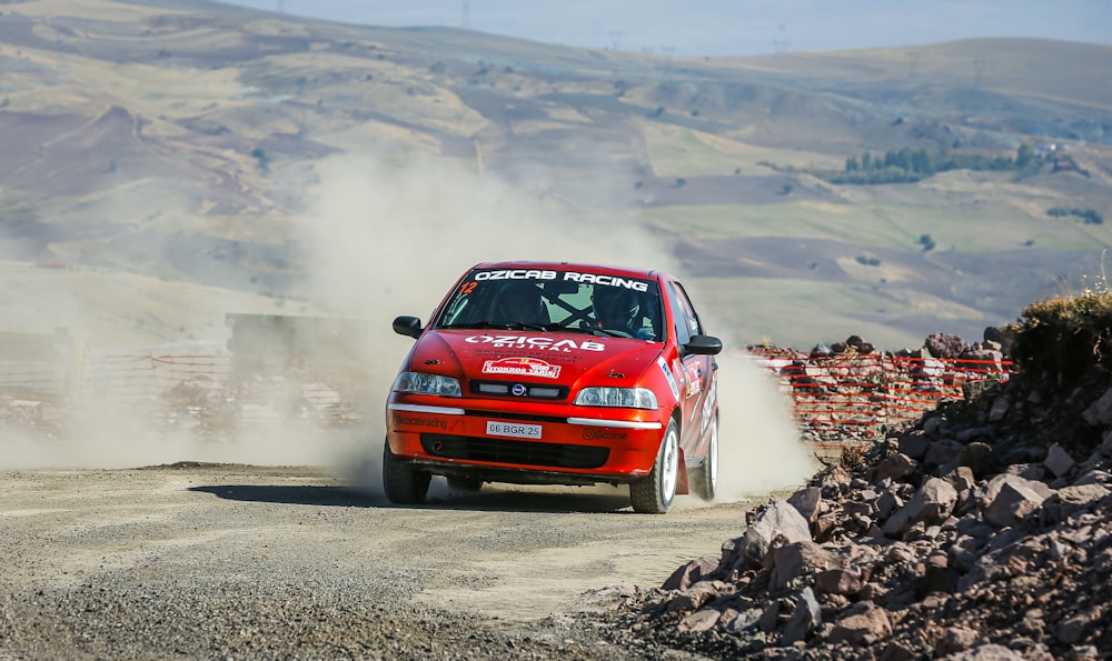 a red car driving down a dirt road