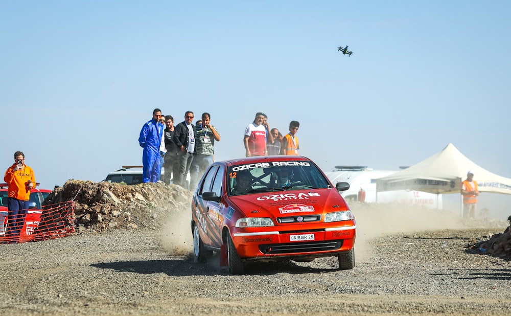 a red car driving down a dirt road