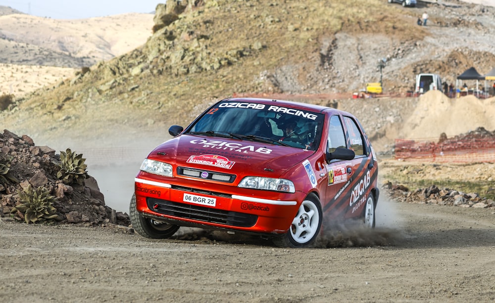 a red car driving down a dirt road