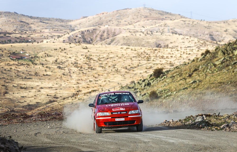 a red car driving down a dirt road