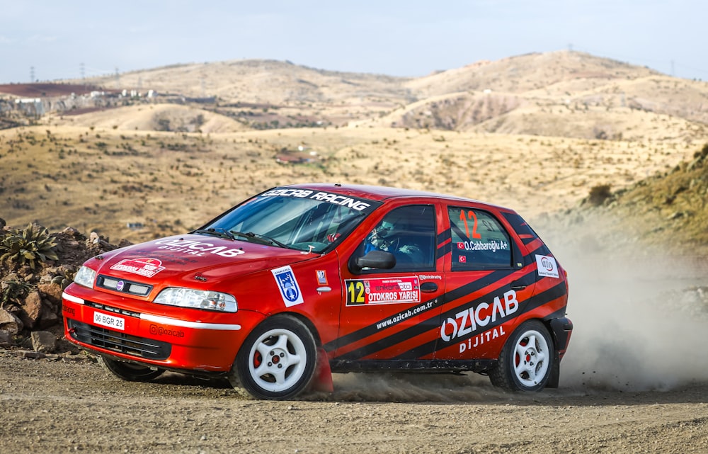 a red car driving down a dirt road