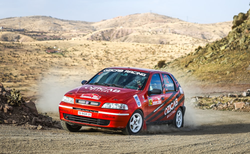 a red car driving down a dirt road