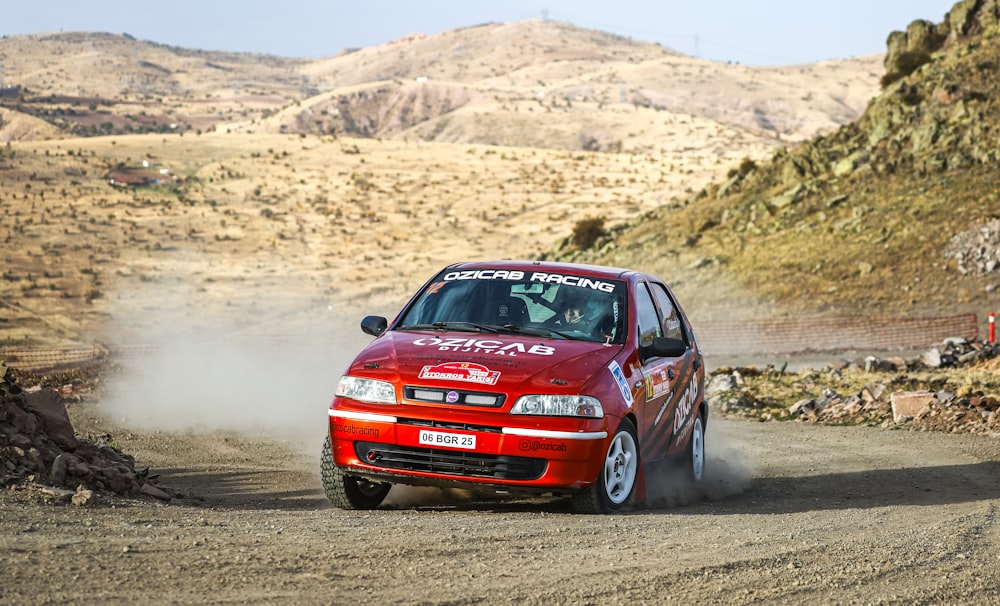 a red car driving down a dirt road