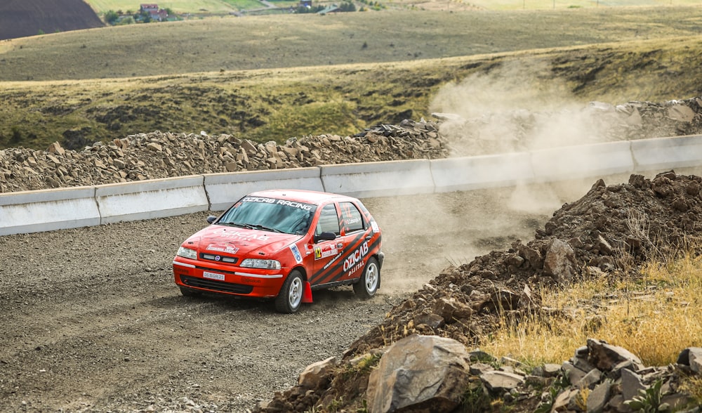 a red car driving down a dirt road