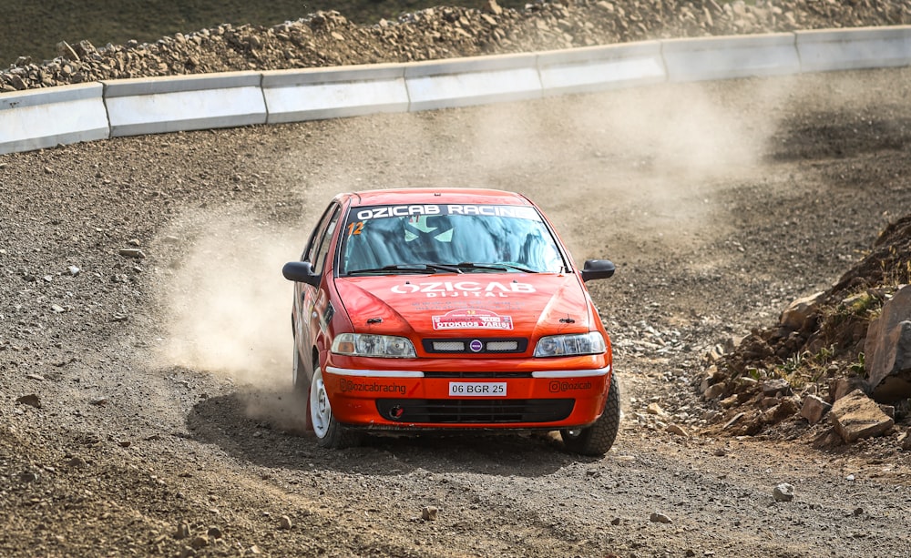 a red car driving down a dirt road