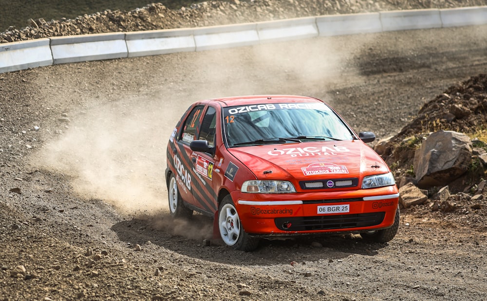 a red car driving down a dirt road