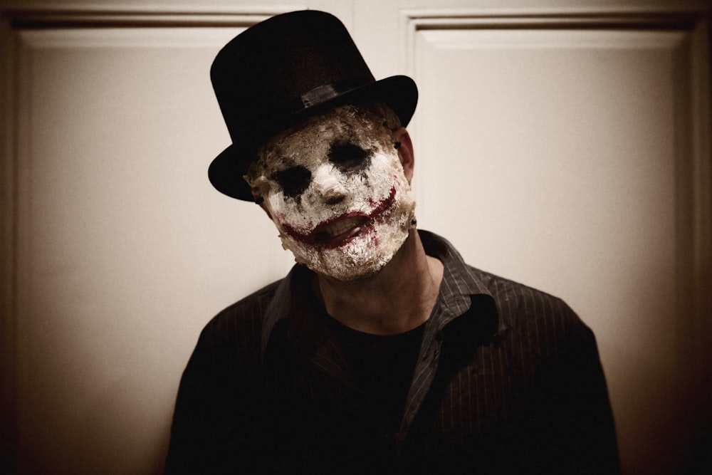 a man wearing a creepy mask and a top hat