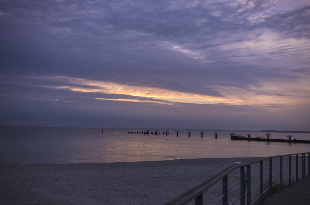 a pier on a beach with a boat in the distance