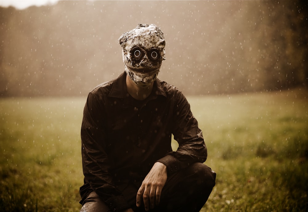 Un hombre con una máscara sentado en un campo