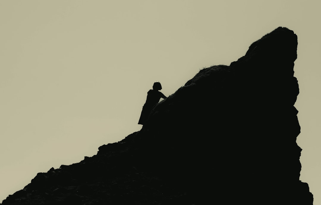 a person sitting on top of a large rock,