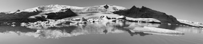 A serene view of a glacier reflecting in a tranquil lake.