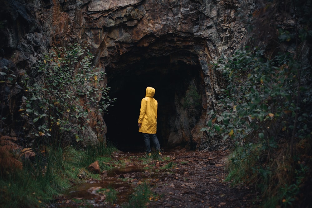 a person in a yellow jacket is standing in a cave