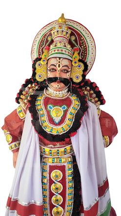 A traditional Yakshagana dancer wearing an elaborate costume with intricate beadwork and colorful embellishments. The headgear is ornate with a detailed design, featuring vibrant reds, yellows, and blues. Facial makeup is distinctive with striking lines and patterns.