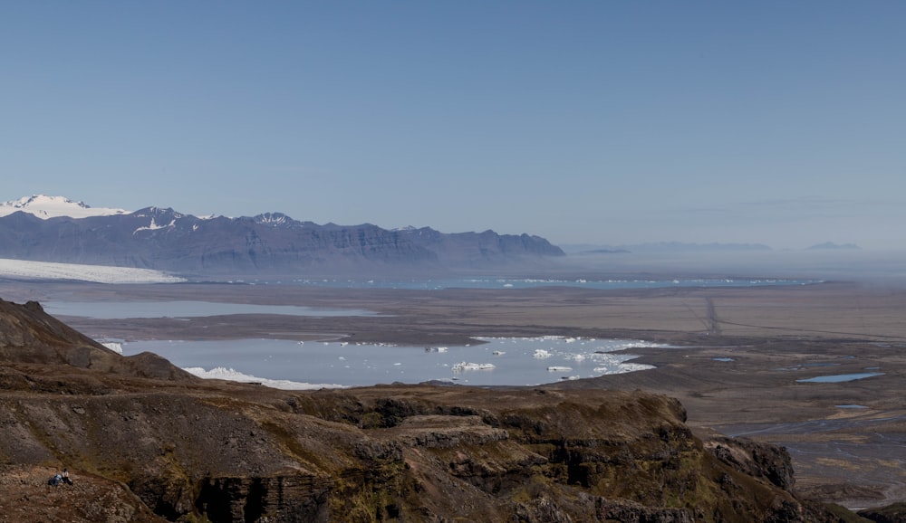 uma vista de uma cordilheira com um lago em primeiro plano