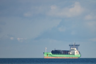 A large cargo ship sailing under a clear blue sky with containers stacked high.