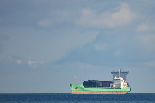A large cargo ship sailing under a clear blue sky with containers stacked high.