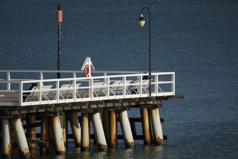 a pier with chairs and a light on top of it