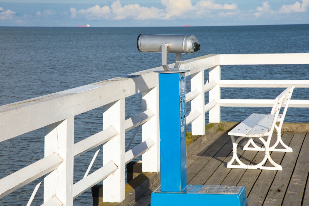 a bench and telescope on a pier overlooking the ocean