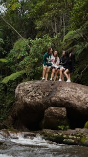 A group of friends laughing together on a nature hike, surrounded by green trees.