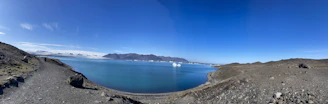 A panoramic shot of Mangla Lake shimmering under a clear blue sky, as seen from Peer Gali.