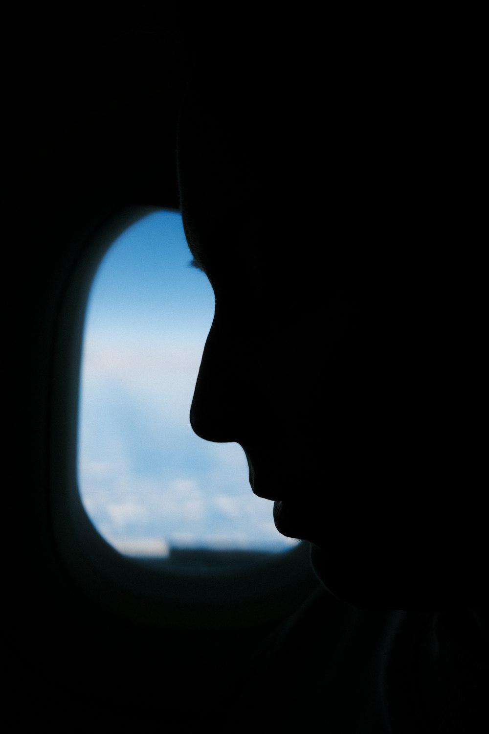 a silhouette of a man looking out an airplane window