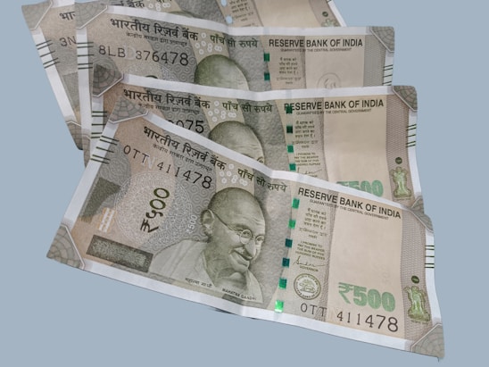 A collection of multiple Indian 500 rupee banknotes fanned out on a flat surface. Each note features a portrait of Mahatma Gandhi and includes text in both Hindi and English. The currency includes security features such as a security thread and watermark.