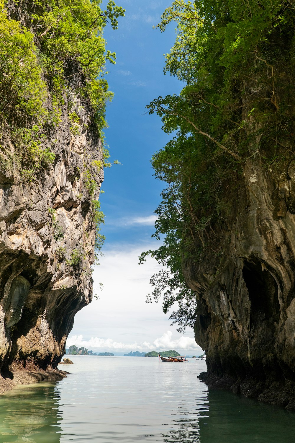 a boat is in the water between two cliffs