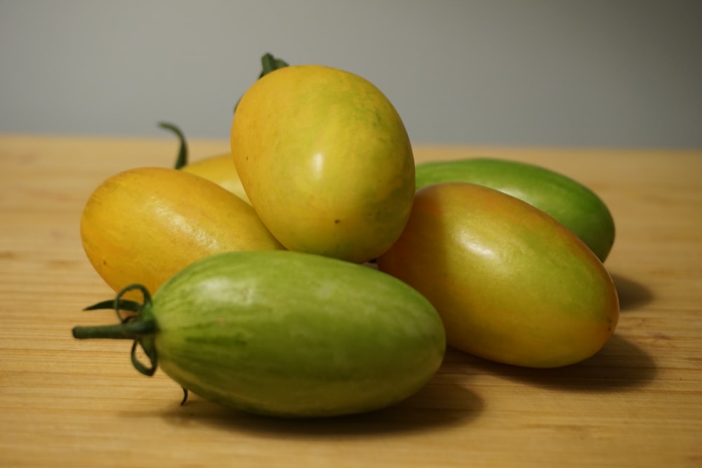 a pile of green and yellow fruit sitting on top of a wooden table
